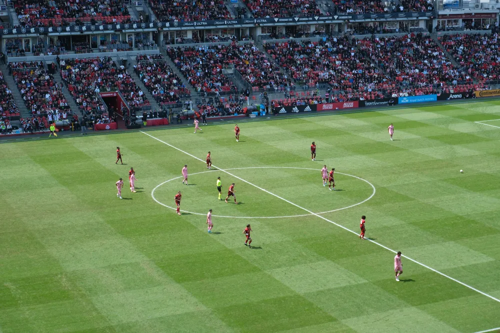 A soccer match seen from the stands of a crowded stadium
