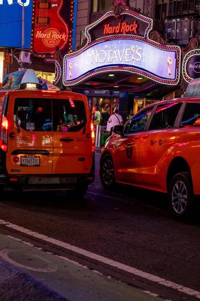 Yellow taxis and glowing theater signs on a city street at night