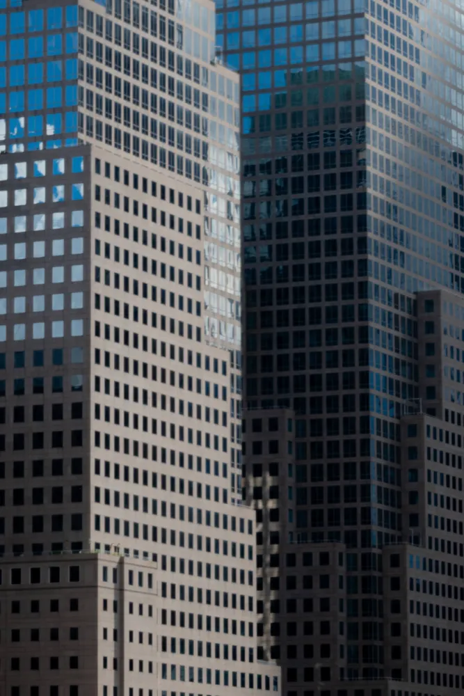 A grid of windows on tall city buildings in blue afternoon light
